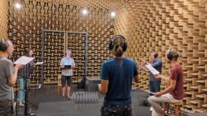 Singers perform with headphones in the sound-absorbing laboratory room.