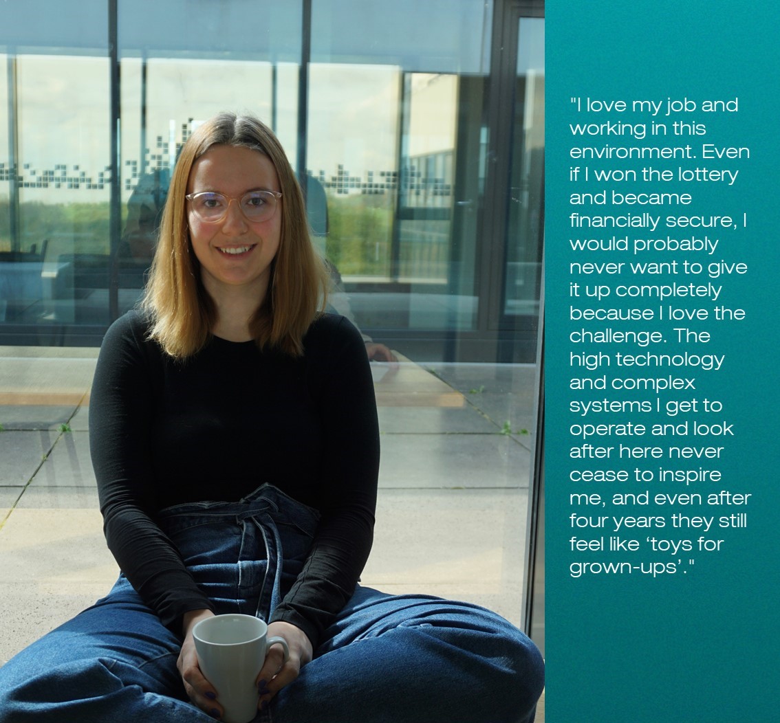 Portrait photo of Rebecca Rodrigo, cross-legged with a coffee cup.