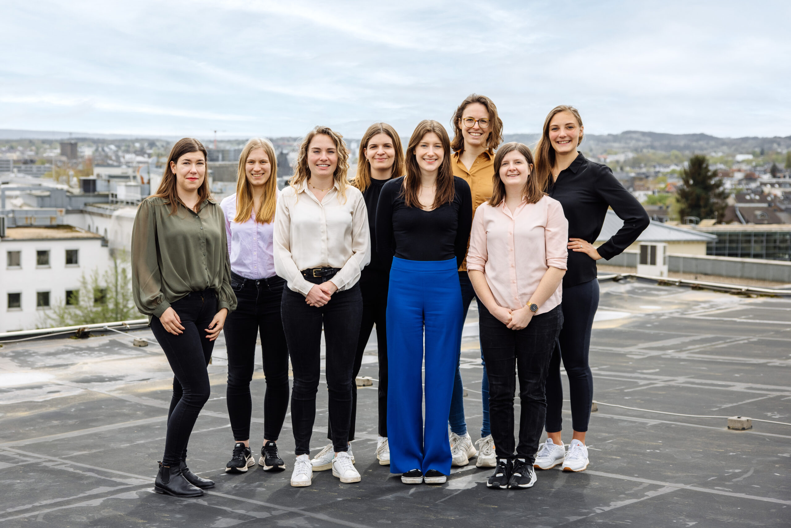 The picture shows eight young women standing in two rows on a roof.