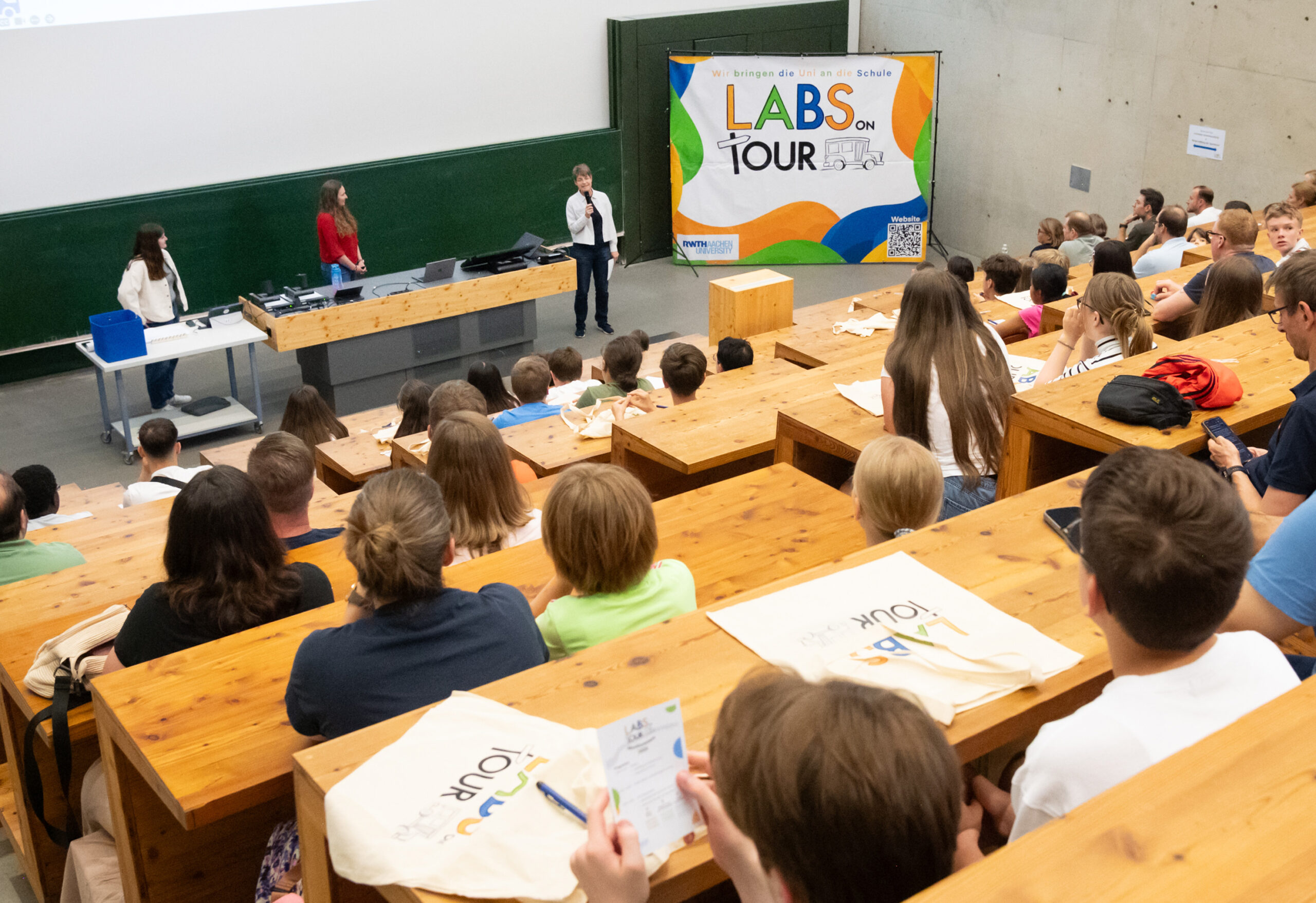 A lecture given in a lecture hall with both children and adults in attendance.