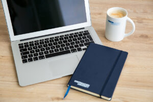 Laptop mit RWTH-Tasse und Notizbuch
