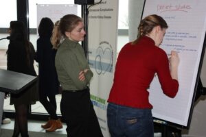 Two people are standing in front of a flipchart at the annual conference of the Transregio 219 collaborative research center.