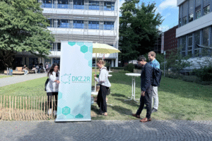 mehrere Personen stehen um ein großes Banner mit der Aufschrift „DKZ.2R“