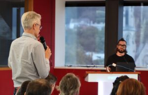 Person with microphone in hand asks a question to a speaker
