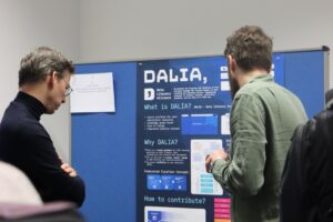 Zwei Personen, die vor einer blauen Tafel mit Informationen zum DALIA-Projekt stehen.