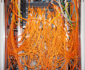 Viele verhädderte orangene Netzerkkabel in einem Switch