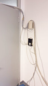 Two patch panels in white with tangled cables on the wall behind a door