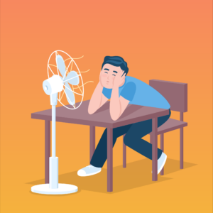 Person sits strained at the desk in front of the fan