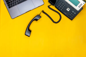 Laptop and telephone on yellow background