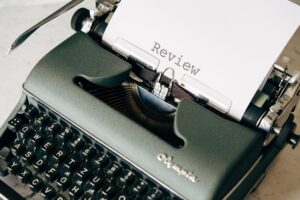 Schreibmaschine mit einem Blatt Papier, auf dem "Review" steht