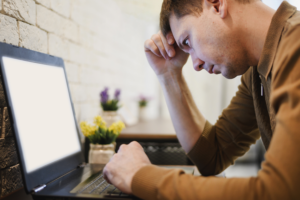 A man sitting in front of his laptop and looking at the screen.