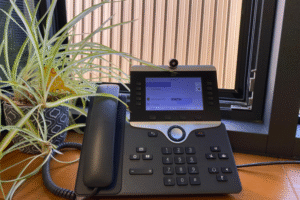 a telephone with a digital display on a wooden windowsill next to a potted green plant