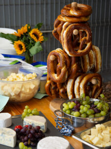 Ein Tisch auf dem Brezeln, Käse und Weintrauben steht.