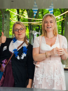Two women in dirndls smile at the camera.