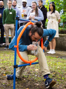 A man climbs through a hoop with a glass of water.