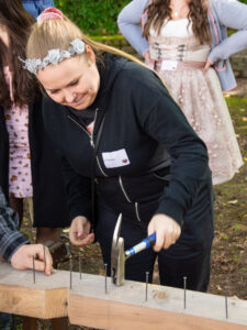A woman is hammering a nail into a beam.