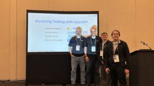 The four speakers stand in front of a screen.