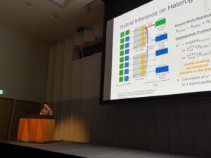 On the left, a person is giving a talk; on the right, there is a large screen displaying a presentation.