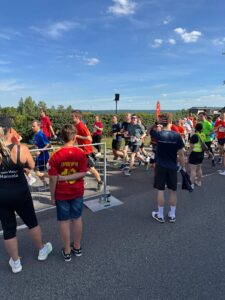 A group of runners at a company run, spectators are standing on the sidelines