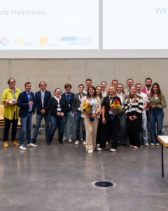 Gruppenfoto mit Helfenden der DINIZKI Tagung auf der Veranstaltungsfläche alle schauen lächelnd in die Kamera