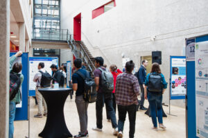 Several people are walking through a foyer and looking at billboards.
