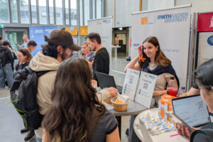 People at an exhibition booth using a laptop.